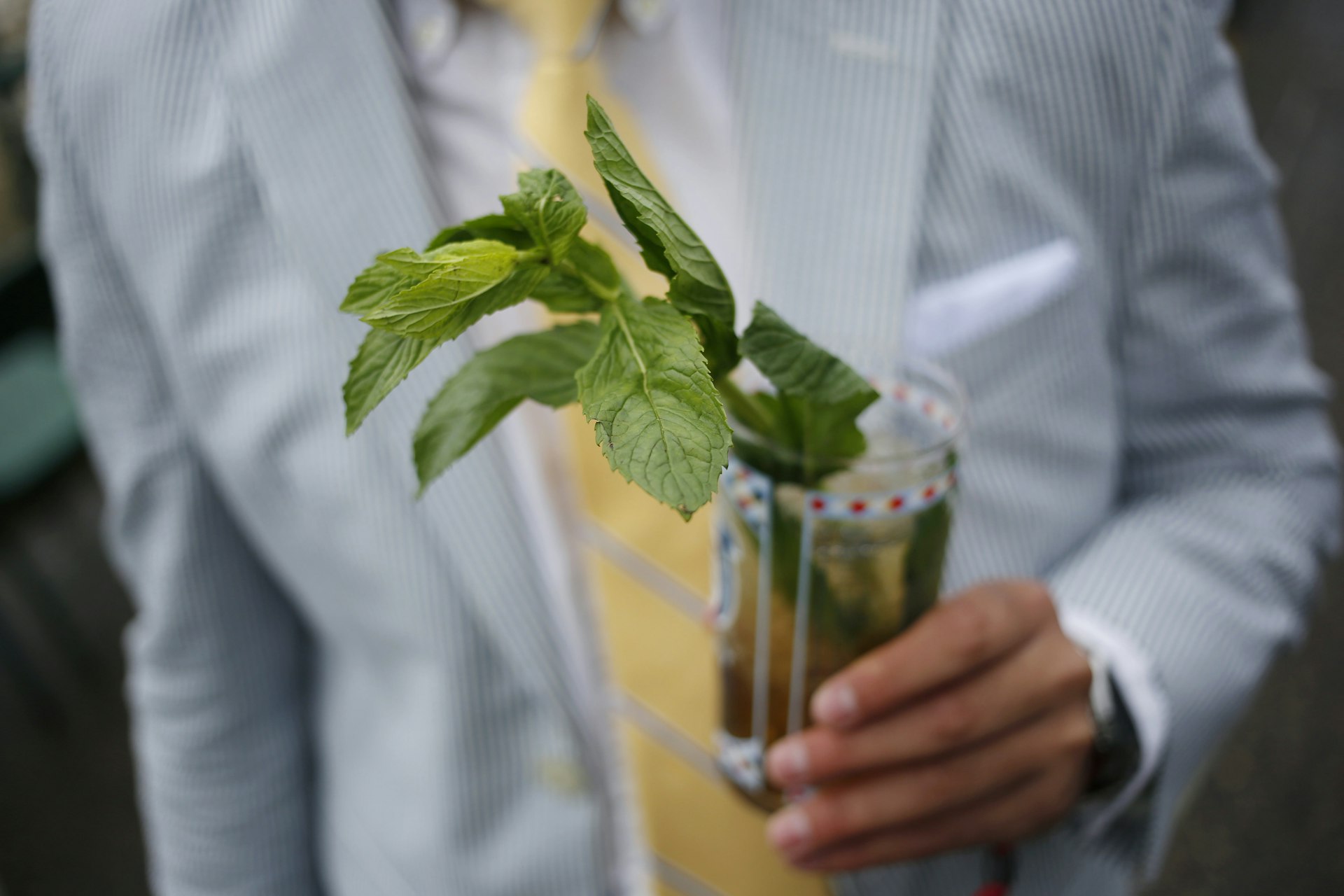 A racegoer holds a mint julep cocktail