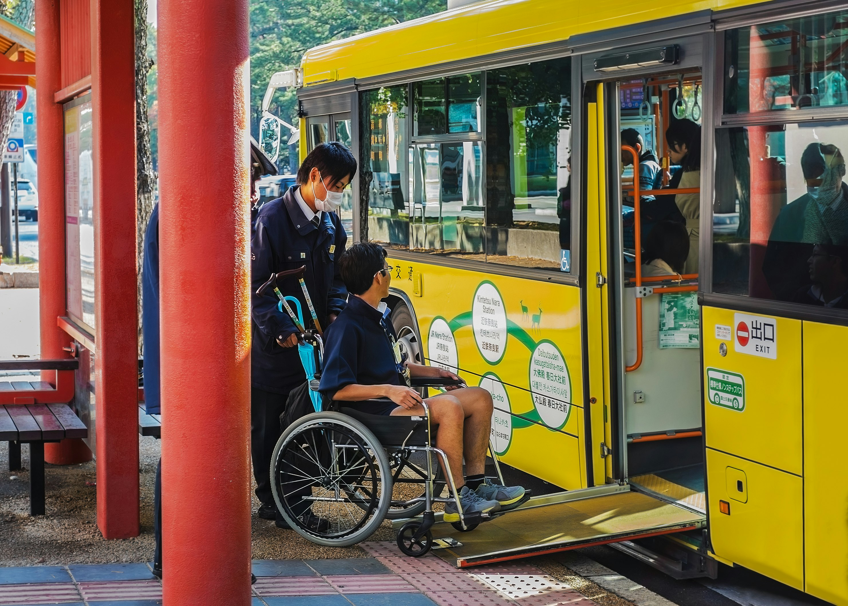 A man in a wheelchair is helped onto a bus, via a temporary ramp, in Nara, Japan.