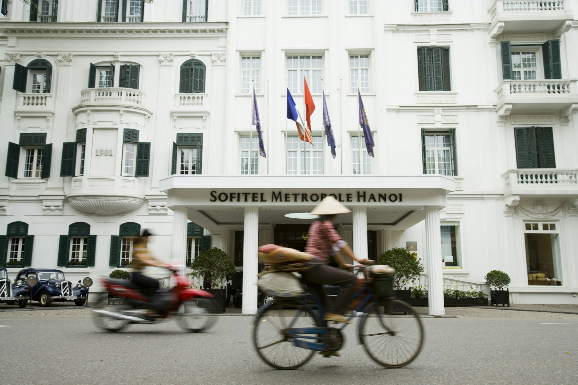 A man on a bicycle rides past a fancy colonial-era building in Hanoi's French Quarter.