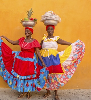 Two Palenqueras, colourfully dressed fruit vendors, in Old Town in Cartagena, Colombia.