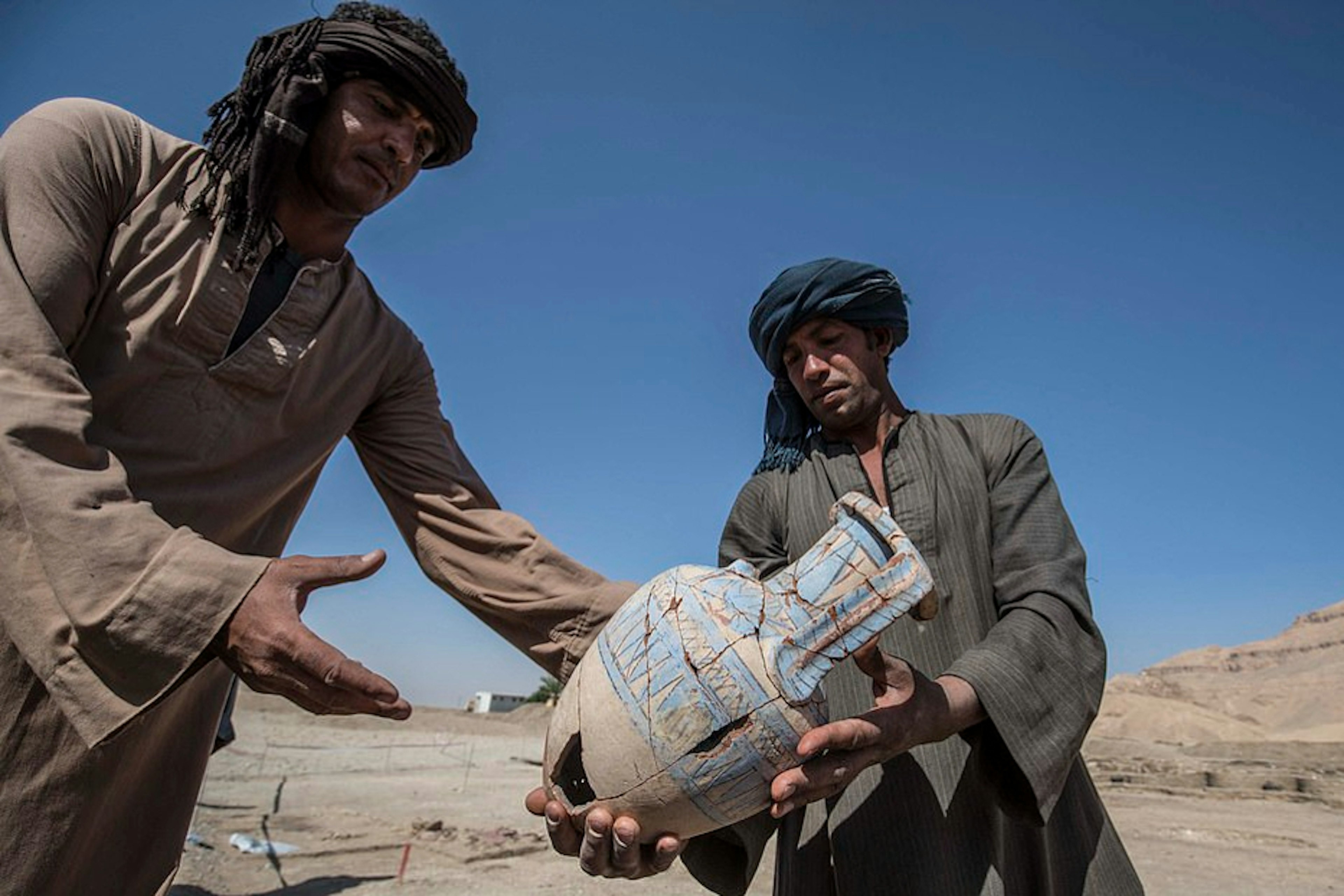 Two men examining a jug found at the city at the Palace of Dazzling Aten in Egypt