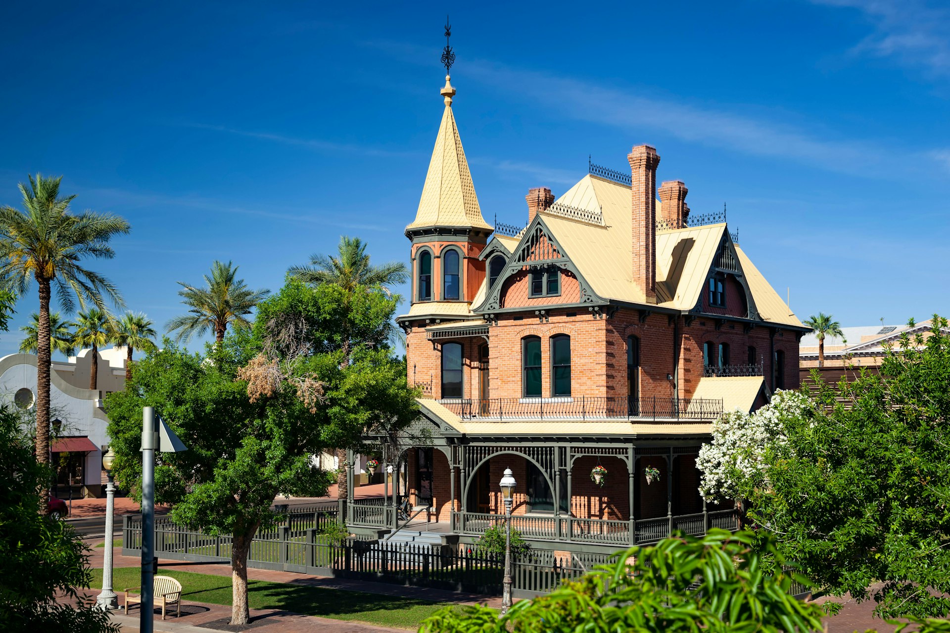 The turrets and yellow roof of the Victorian-style Rosson House Museum on Heritage Square Park, Phoenix, Arizona in the USA peep through green trees on a clear afternoon