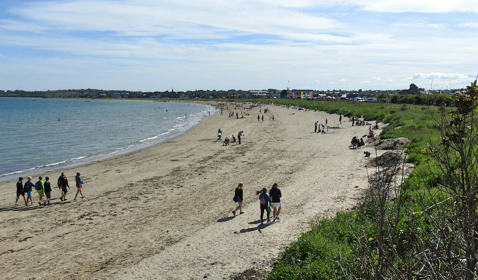 People walk along Skerries Beach on a summer day
