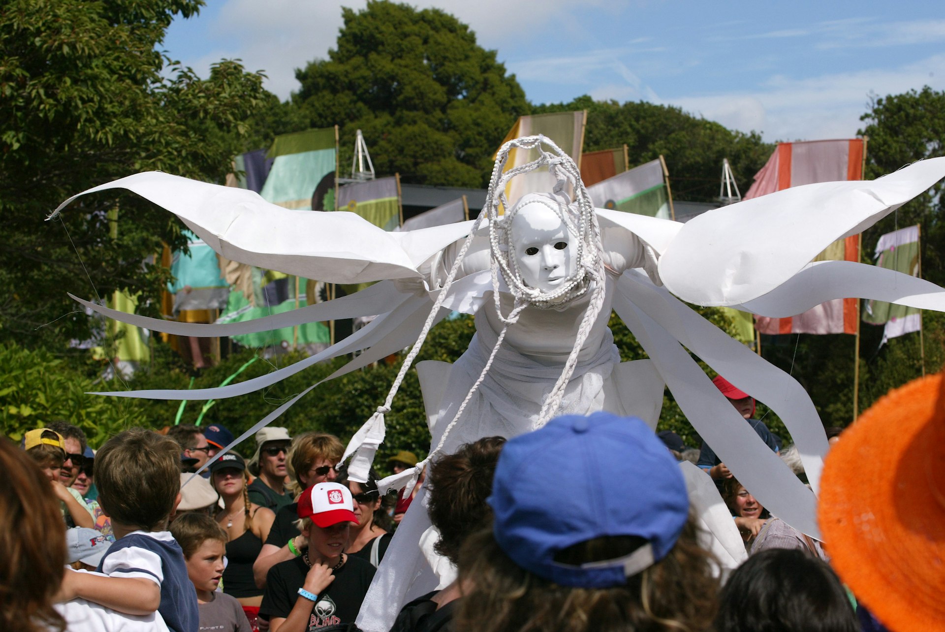A person in a white costume and mask at the WOMAD