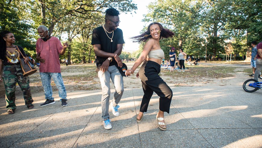 Two people smile and dance in the park