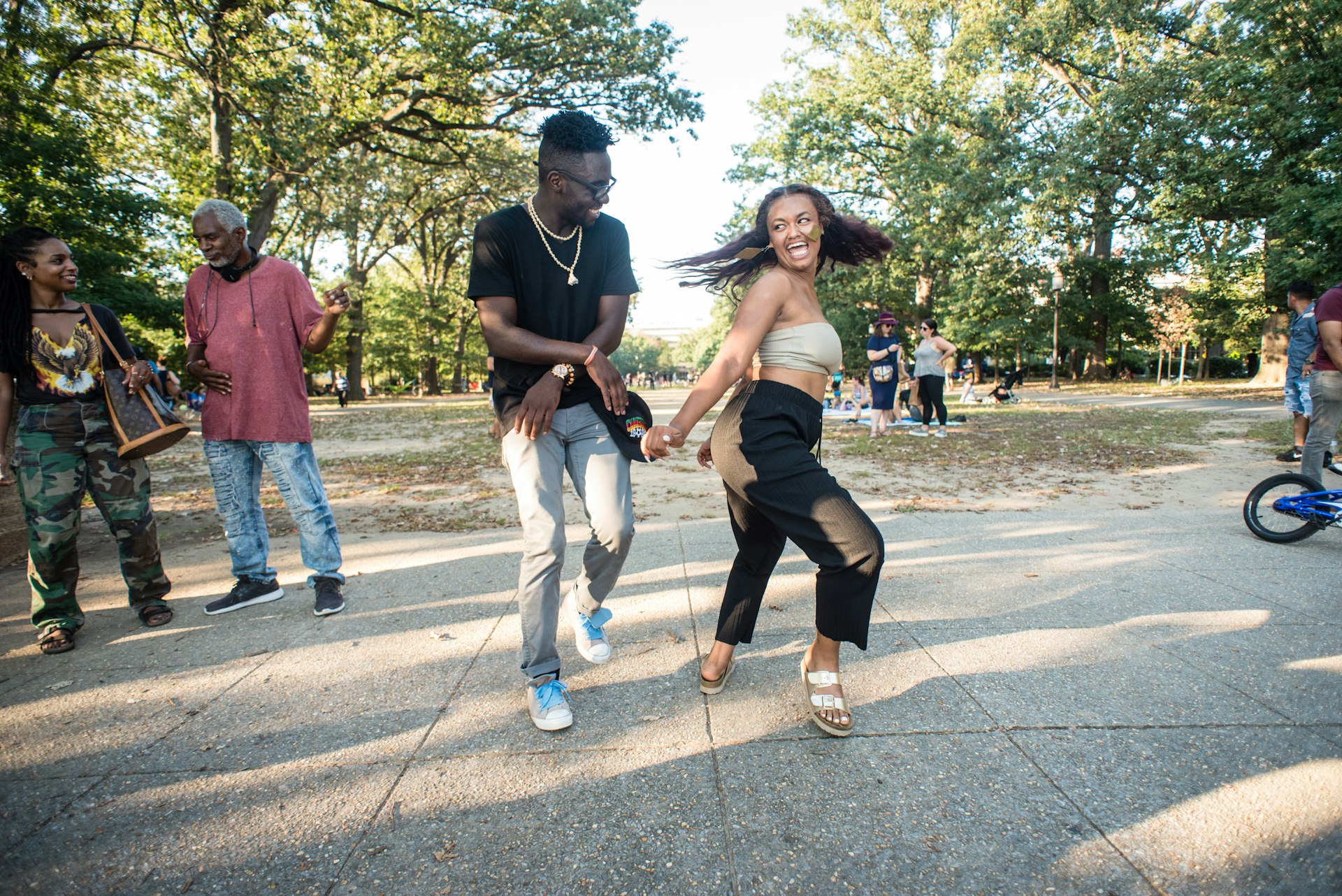 Two people smile and dance in the park
