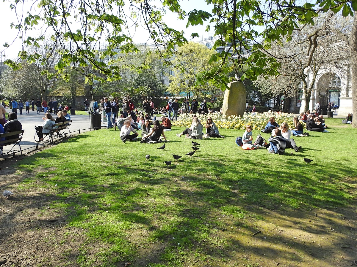 March 29, 2019: Crowd of people sitting on the grass in St Stephen's Green city centre public park on a hot sunny day.
