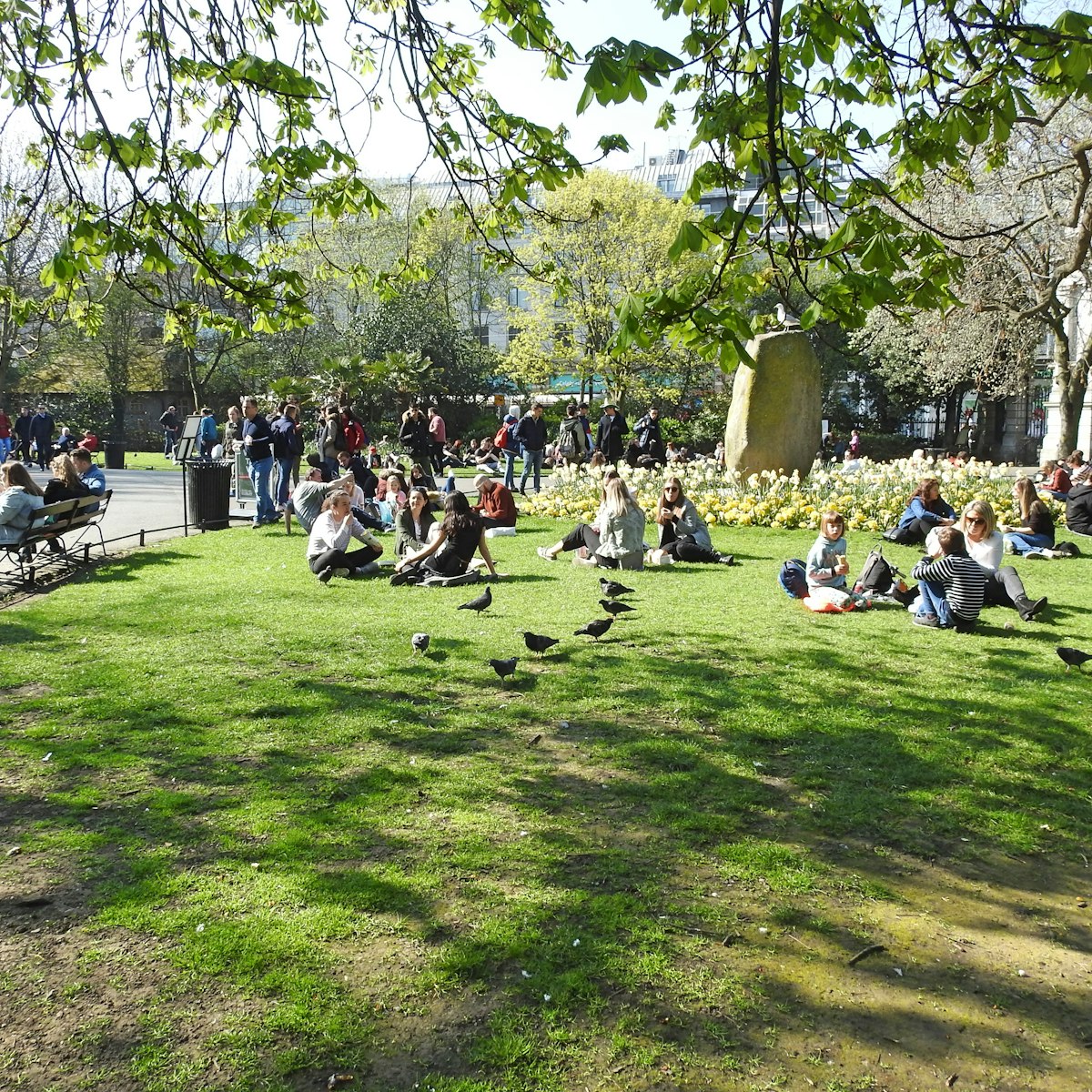 March 29, 2019: Crowd of people sitting on the grass in St Stephen's Green city centre public park on a hot sunny day.
