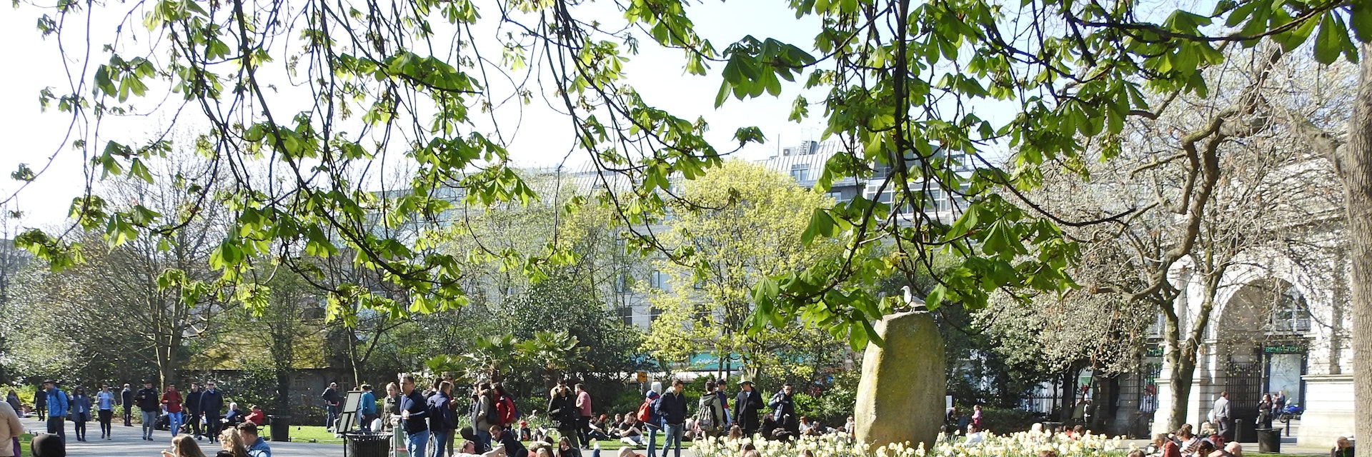 March 29, 2019: Crowd of people sitting on the grass in St Stephen's Green city centre public park on a hot sunny day.
