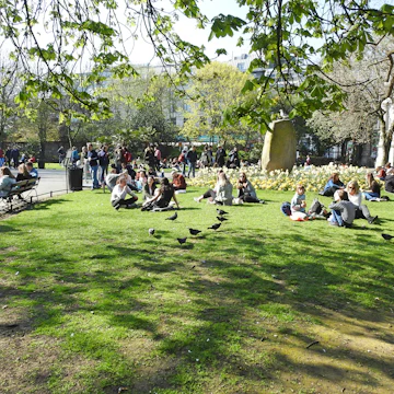 March 29, 2019: Crowd of people sitting on the grass in St Stephen's Green city centre public park on a hot sunny day.
