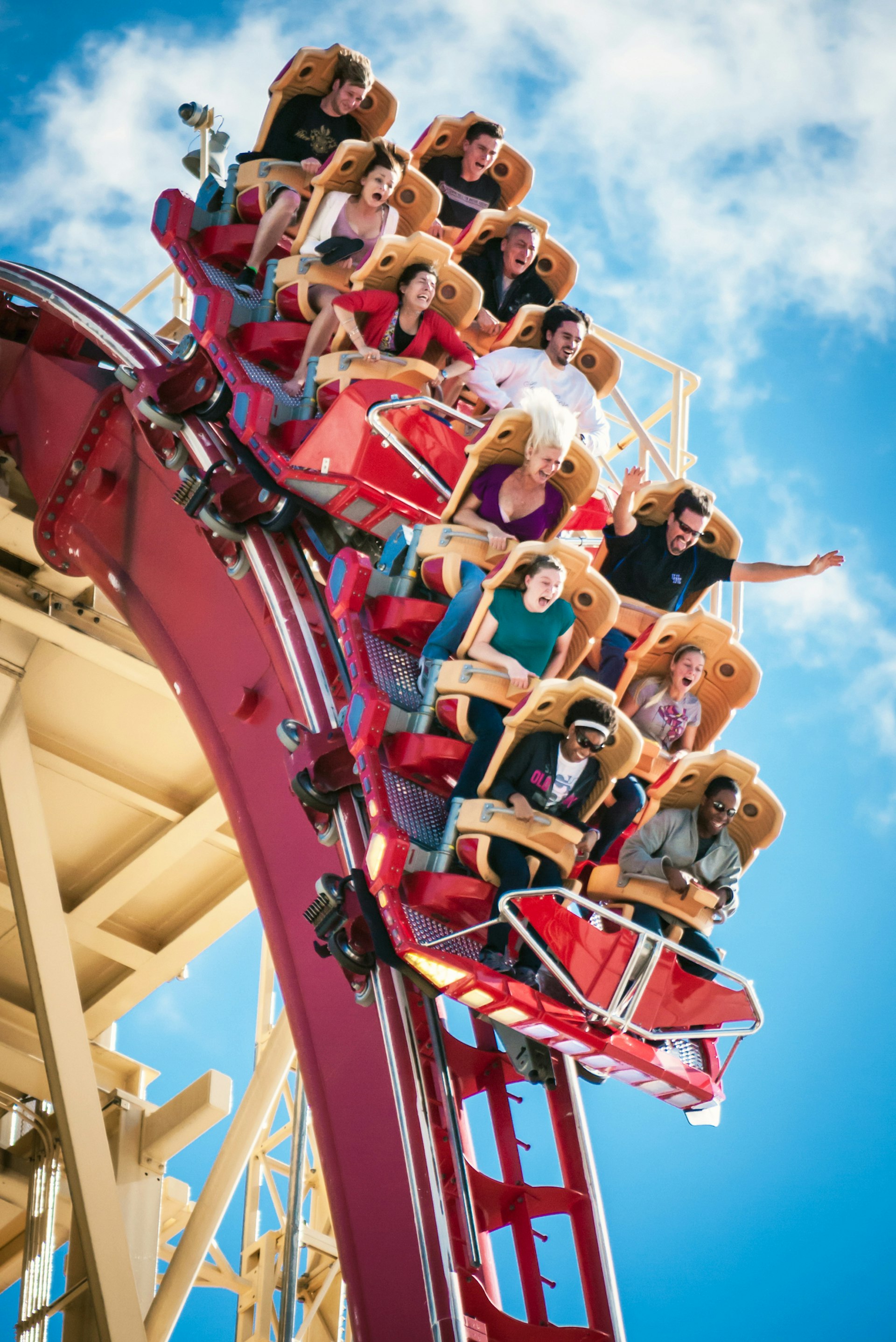 A rollercoaster dropping down from its peak. Passengers have expressions showing a mix of fear, excitement and fun