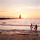 Kids playing in the water in front of St Joseph Lighthouse on Lake Michigan during sunset.