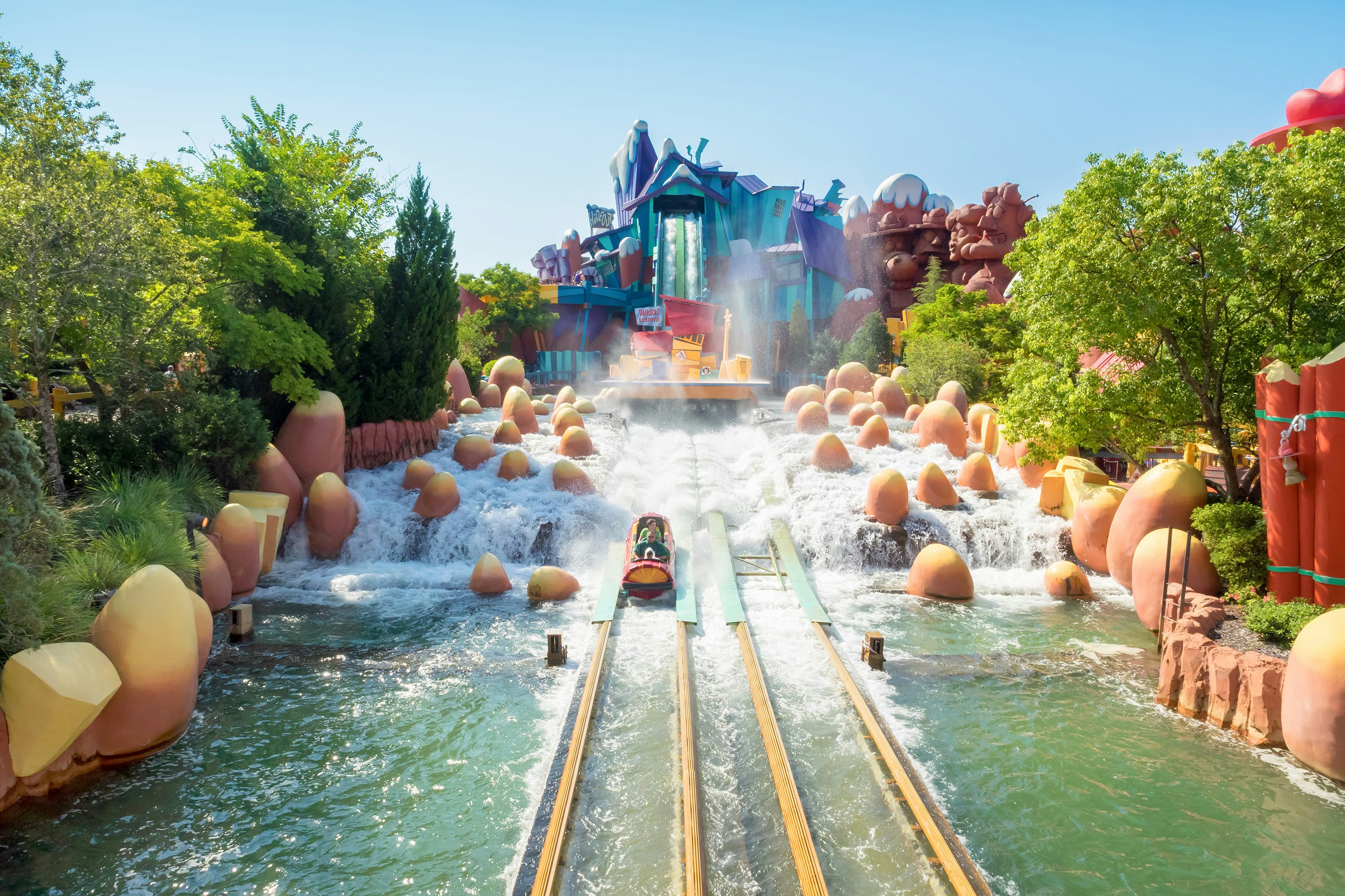 Water sprays around people riding down a log flume at a Florida theme park on a sunny day.