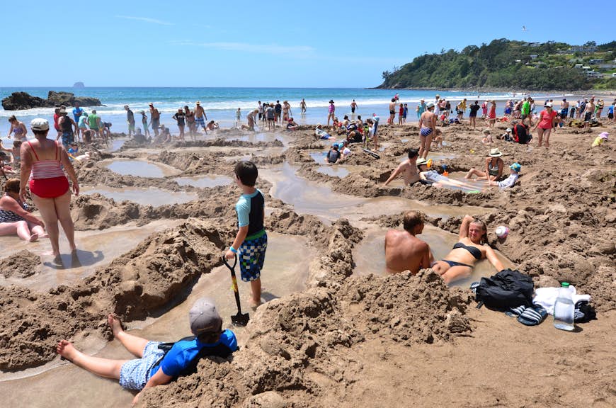 Visitors making small hot water pools in Hot Water beach.it is one of the most popular geothermal attractions in New Zealand, about 700,000 people visit the beach annually. 