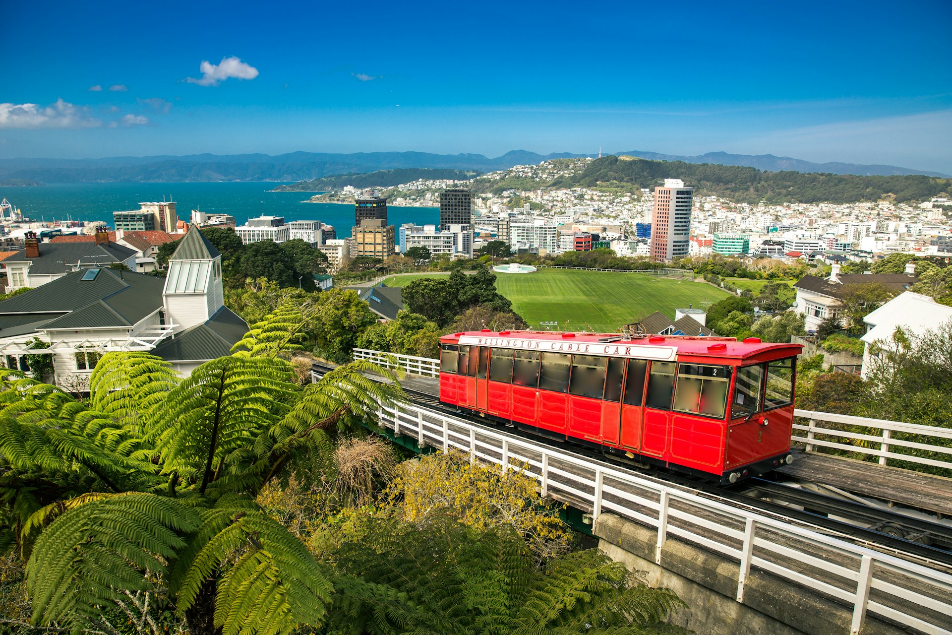 A red cable car rises above a cityscape. 