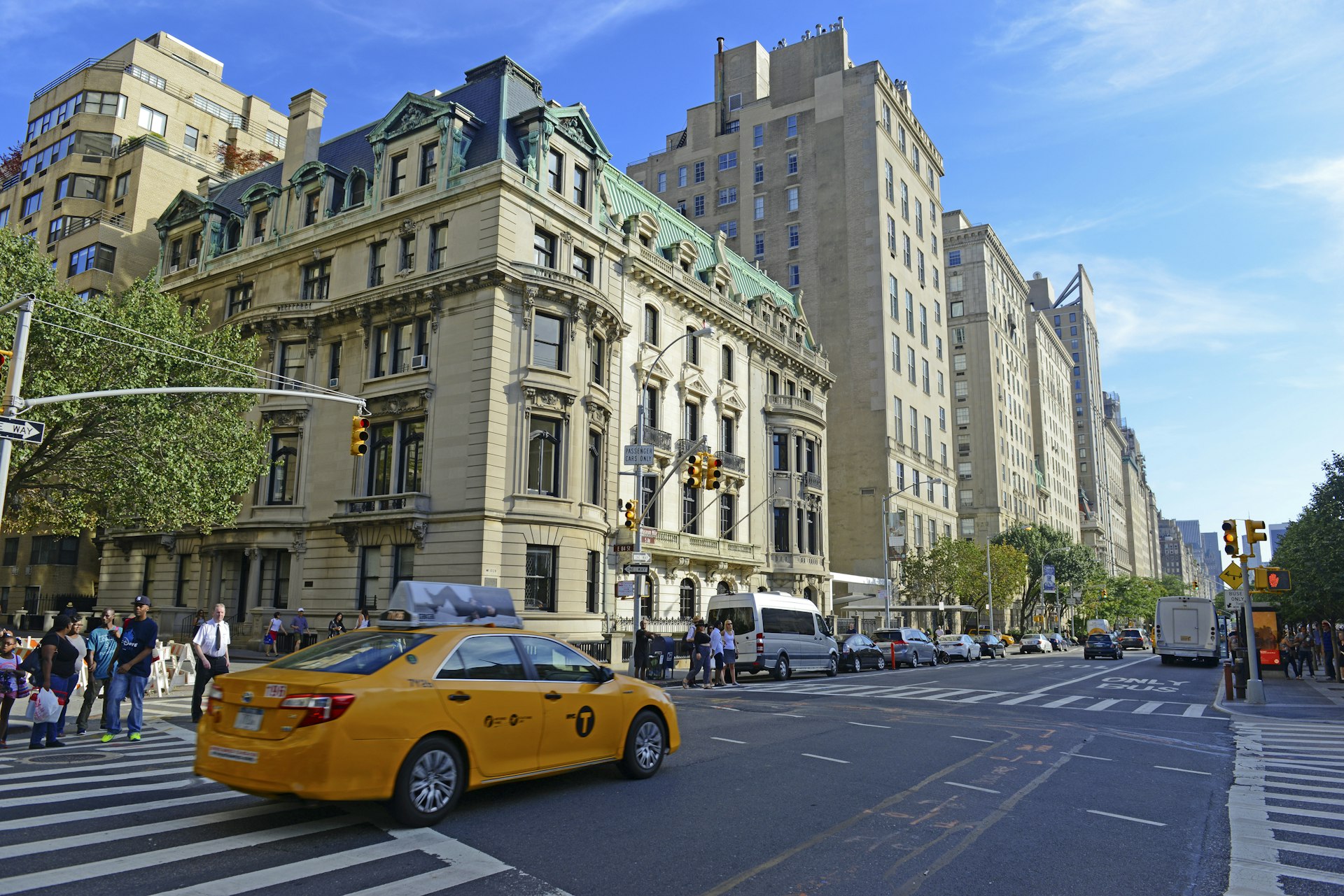 A yellow New York City cab drives past a luxury brick building on the Upper East Side