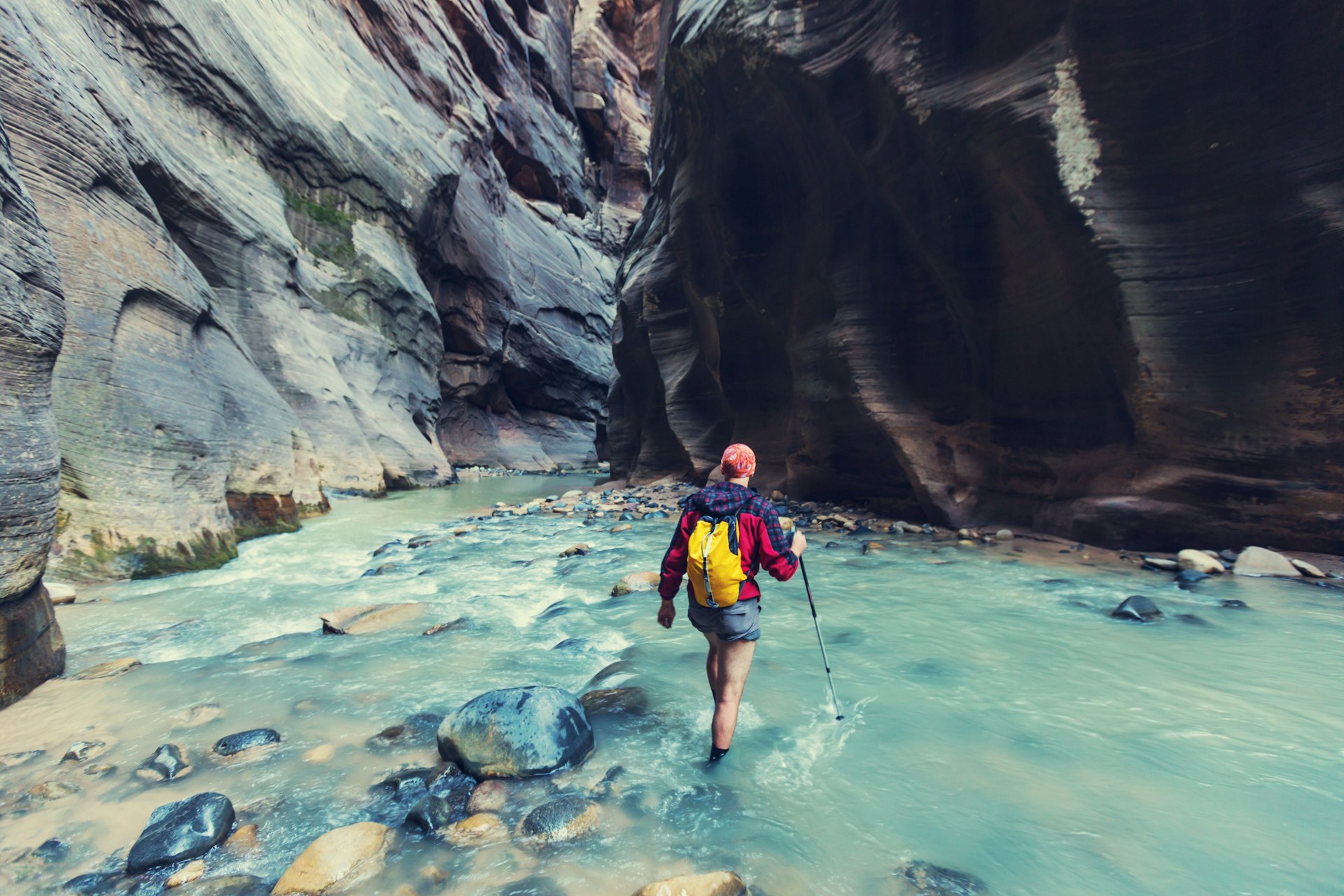 A hiker wades through water in the Narrows in Zion National Park