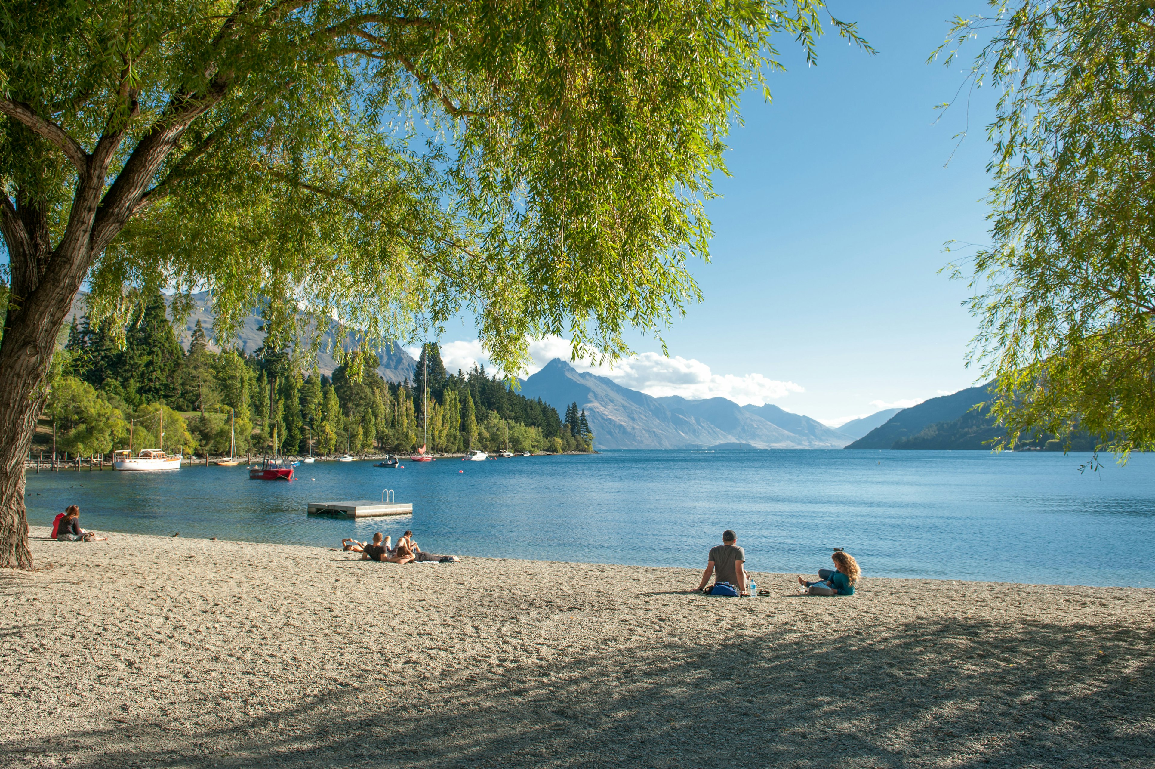 Visitors relax on the shore of Lake Wakatipu in Queenstown