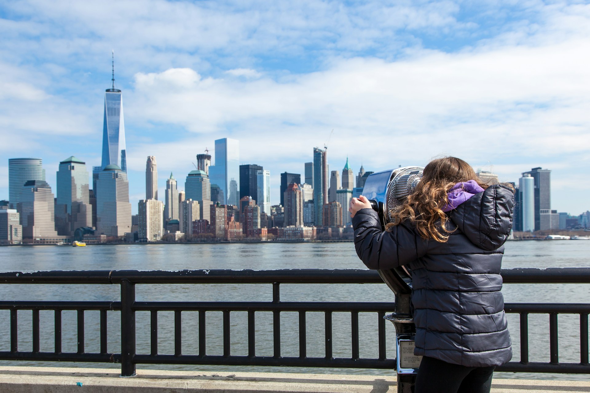 A little girl looks at the Manhattan skyline through binoculars at Liberty State Park
