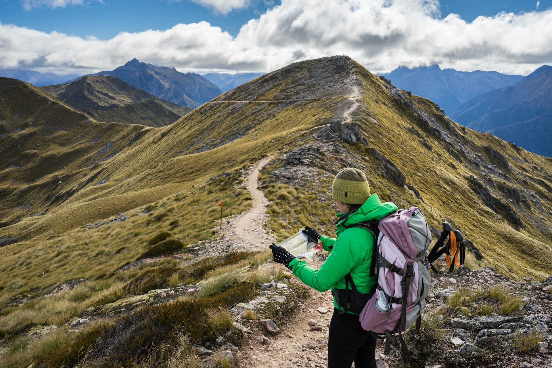Female hiker looking at a map on a mountainous section of a hiking trail. 