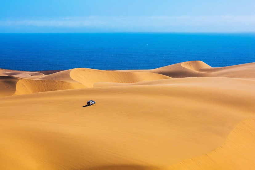 A lone jeep explores the dunes of Sandwich Harbour, part of Namib-Naukluft National Park.