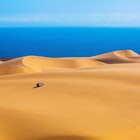 A lone jeep explores the dunes of Sandwich Harbour, part of Namib-Naukluft National Park.