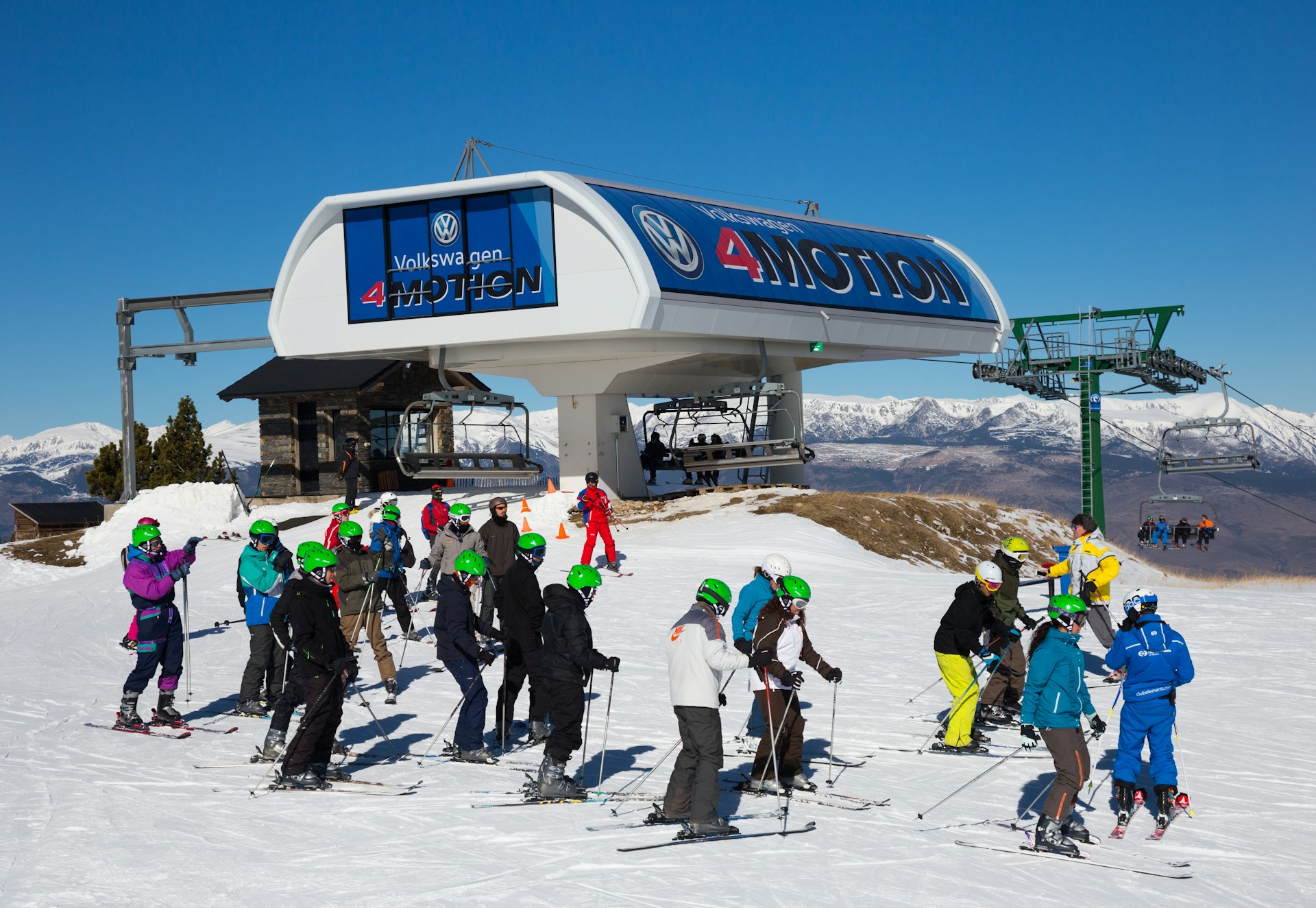 Skiers on a snowy mountaintop with a chairlift station in the background