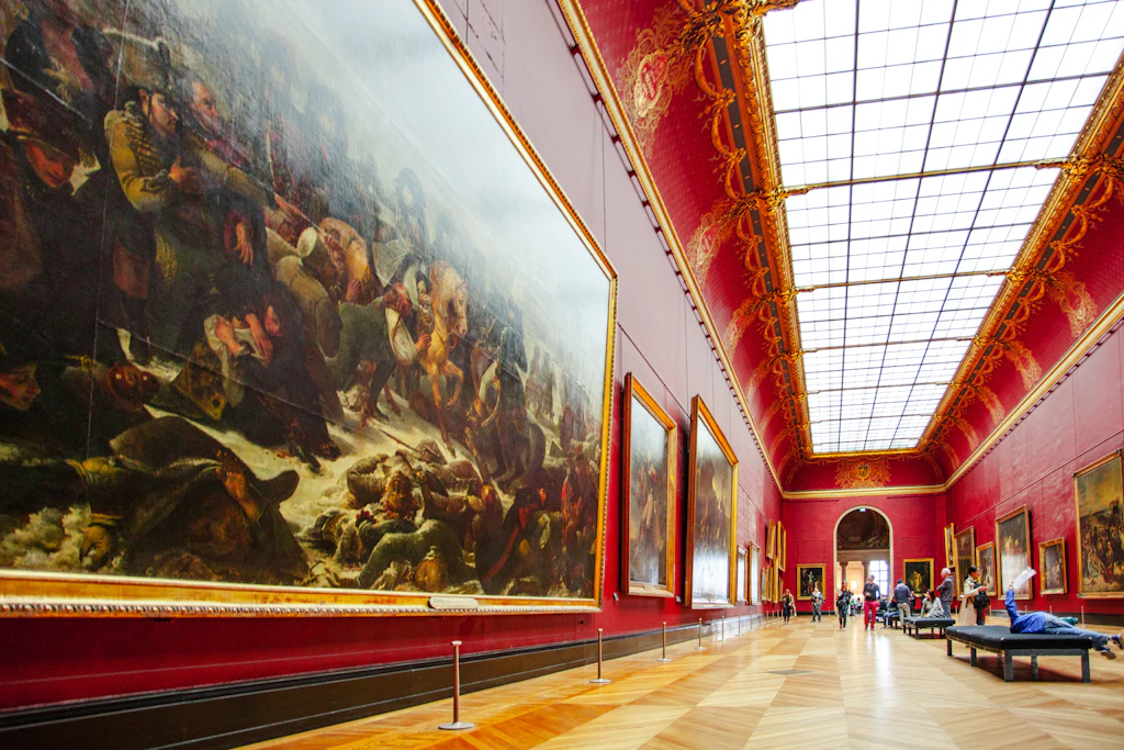 The Louvre Visitors inside a red gallery space in the Louvre Museum.
