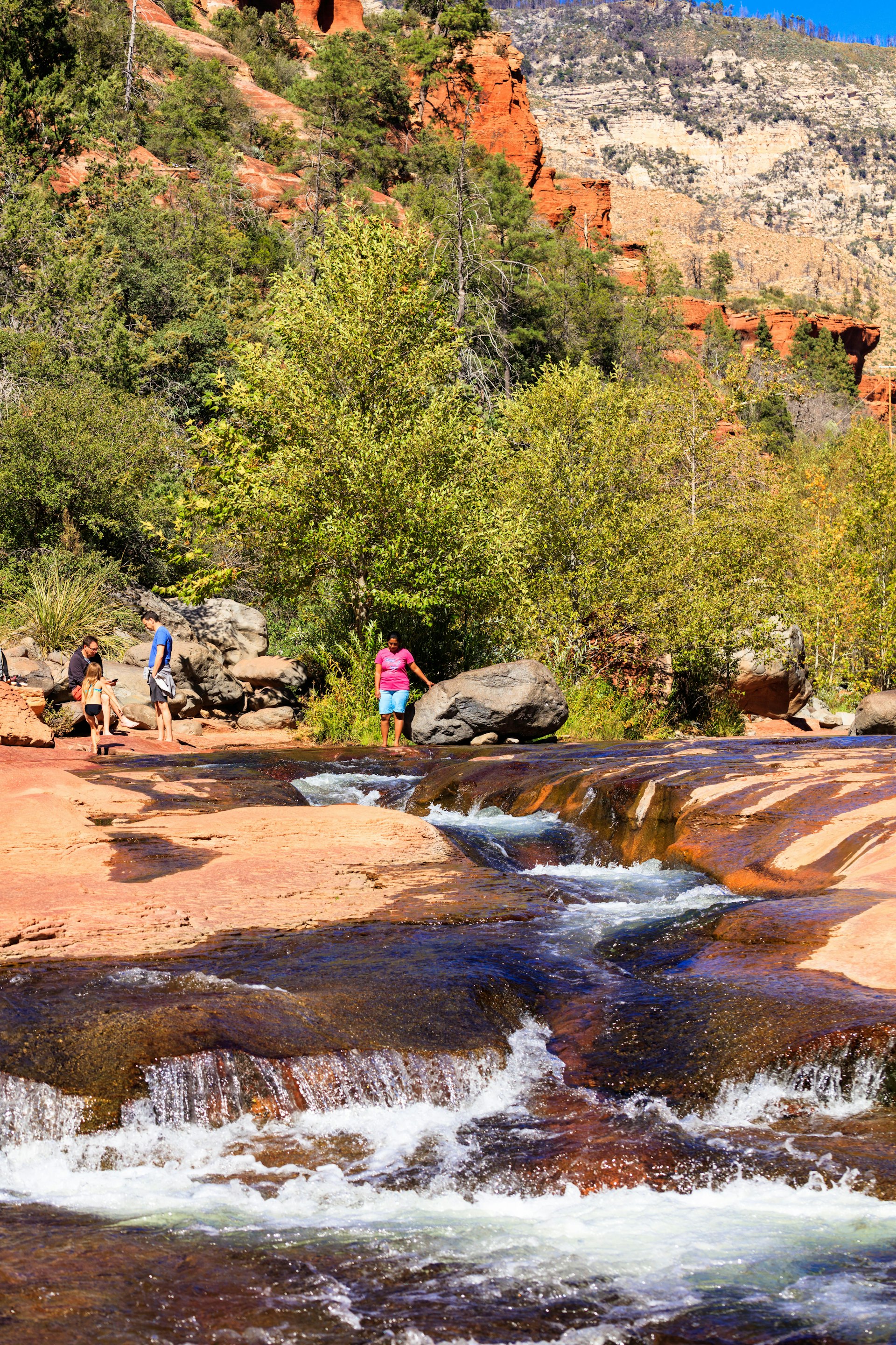 Visitors enjoying the beauty of Slide Rock State Park with its natural rock water slides in the Oak Creek Canyon