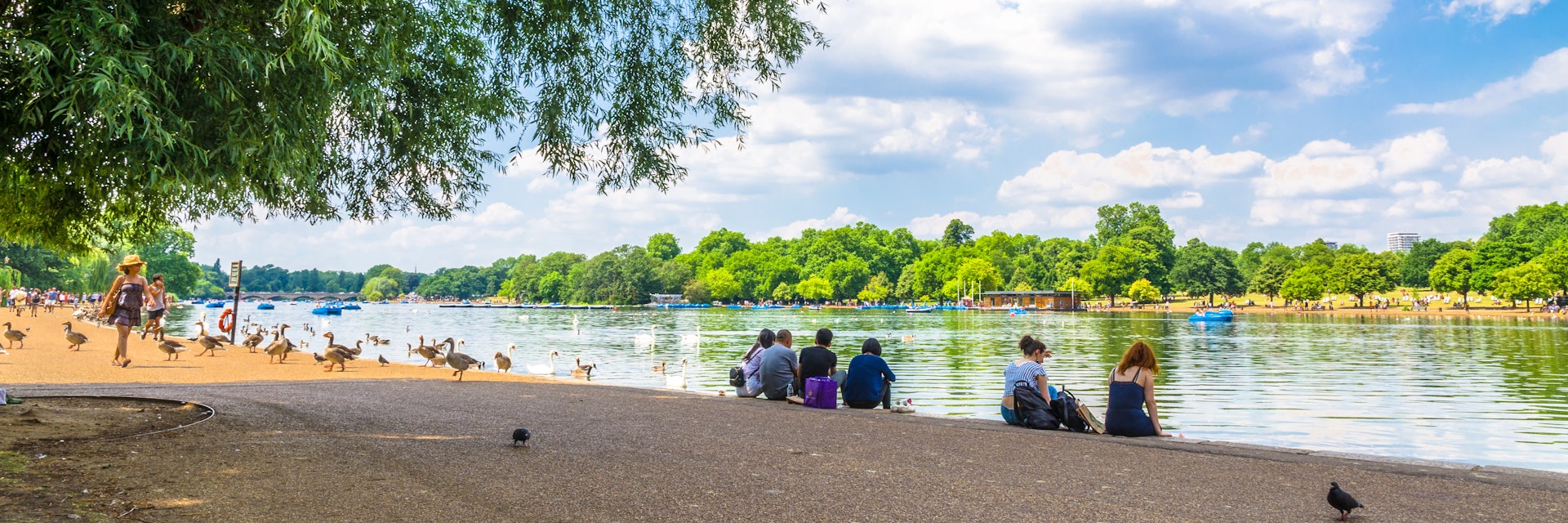 JUNE 18, 2017: Visitors seated on the shore of Serpentine Lake in Hyde Park.