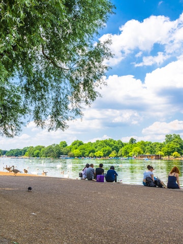 JUNE 18, 2017: Visitors seated on the shore of Serpentine Lake in Hyde Park.