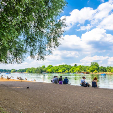 JUNE 18, 2017: Visitors seated on the shore of Serpentine Lake in Hyde Park.