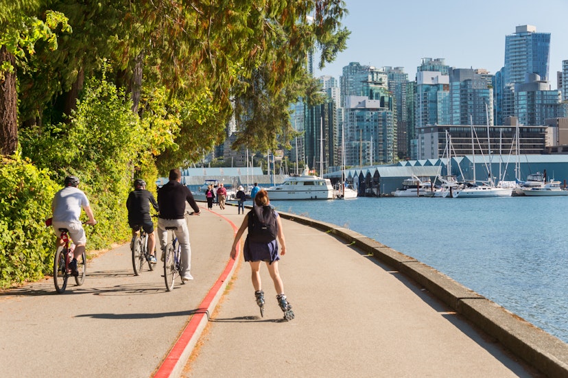 September 14, 2017: Cyclists and a rollerblader on a path in Stanley Park during summer.