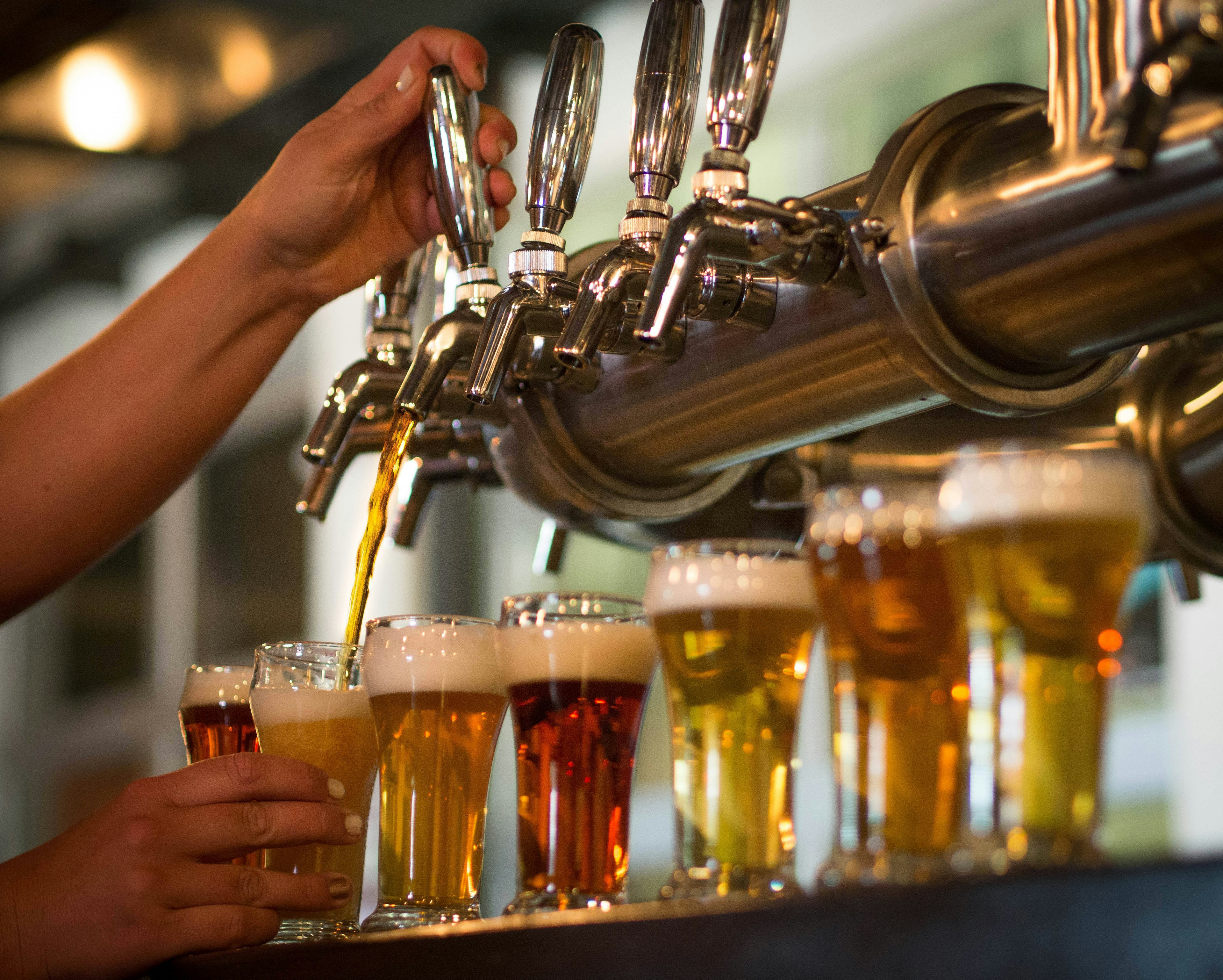 A bartender pours beer from a tap at a craft beer brewery in Colorado