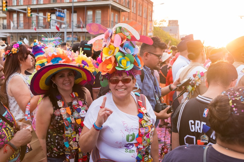 Crowds gather together with people wearing crazy hats medals, and pins duing the opening night celebration of Fiesta San Antonio.