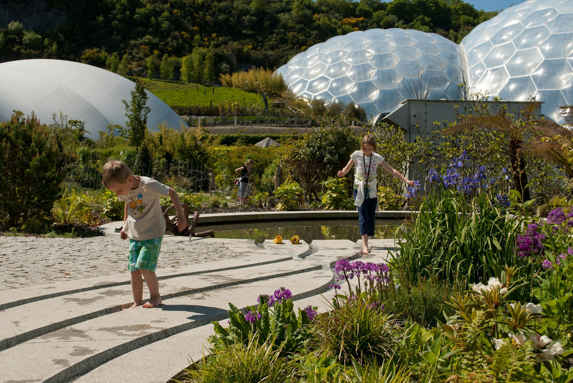 Two young children play in the gardens surrounding huge domes at Eden Project, Cornwall
