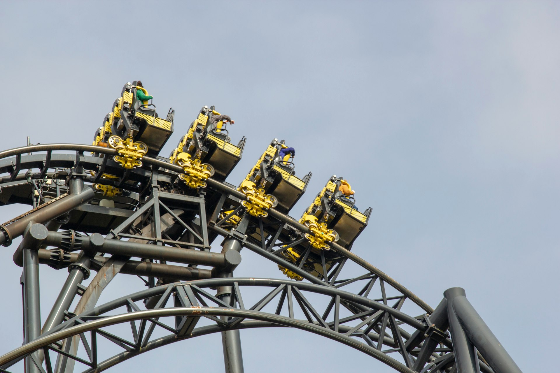 A black-and-yellow rollercoaster with four separate carriages makes its way along a high track