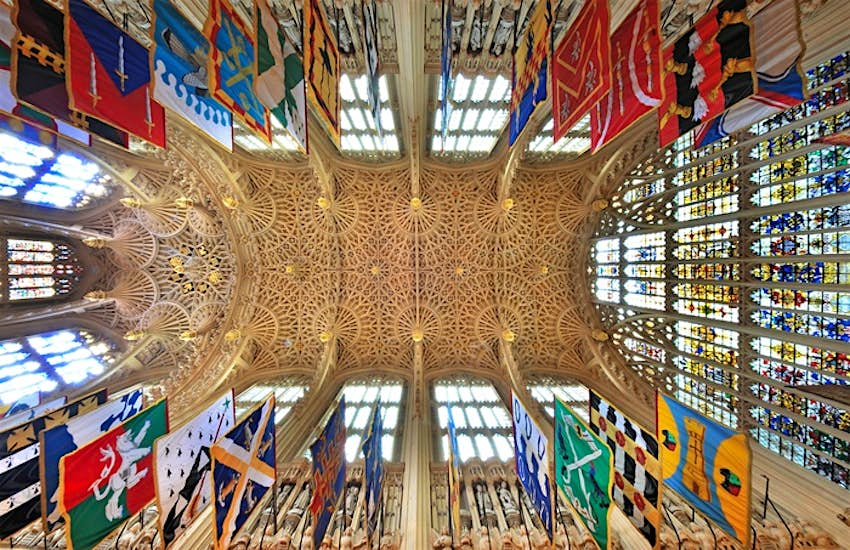 Lady Chapel A shot straight up towards a ceiling with intricate stone webbing across it. There are colorful flags hanging around the walls