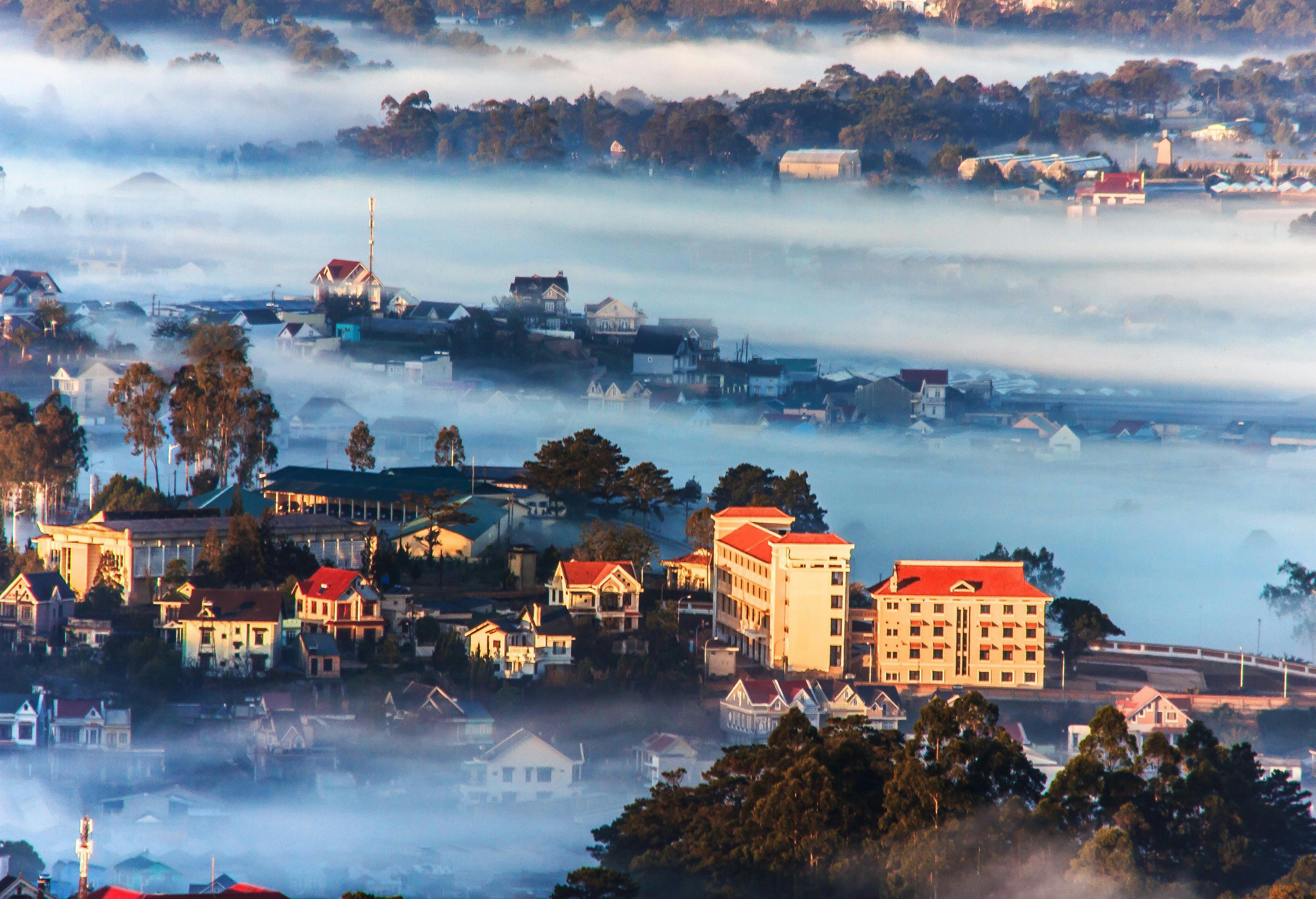 An aerial view overlooking the hill station of Dalat in Vietnam. The town is shroud in mist due to its high altitude, meaning only a few buildings are visible.