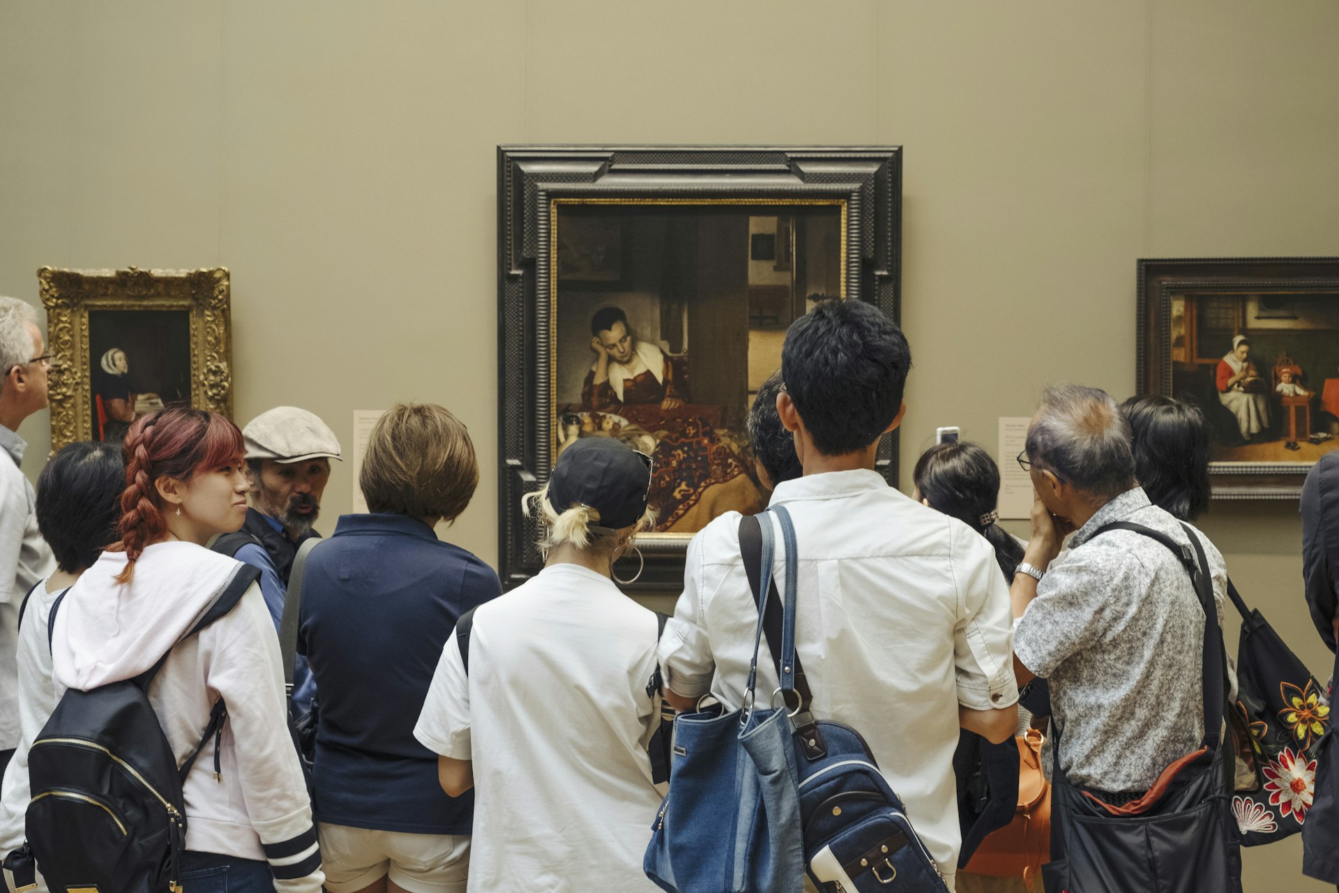 A shot of the backs of a crowd of people inspecting a painting