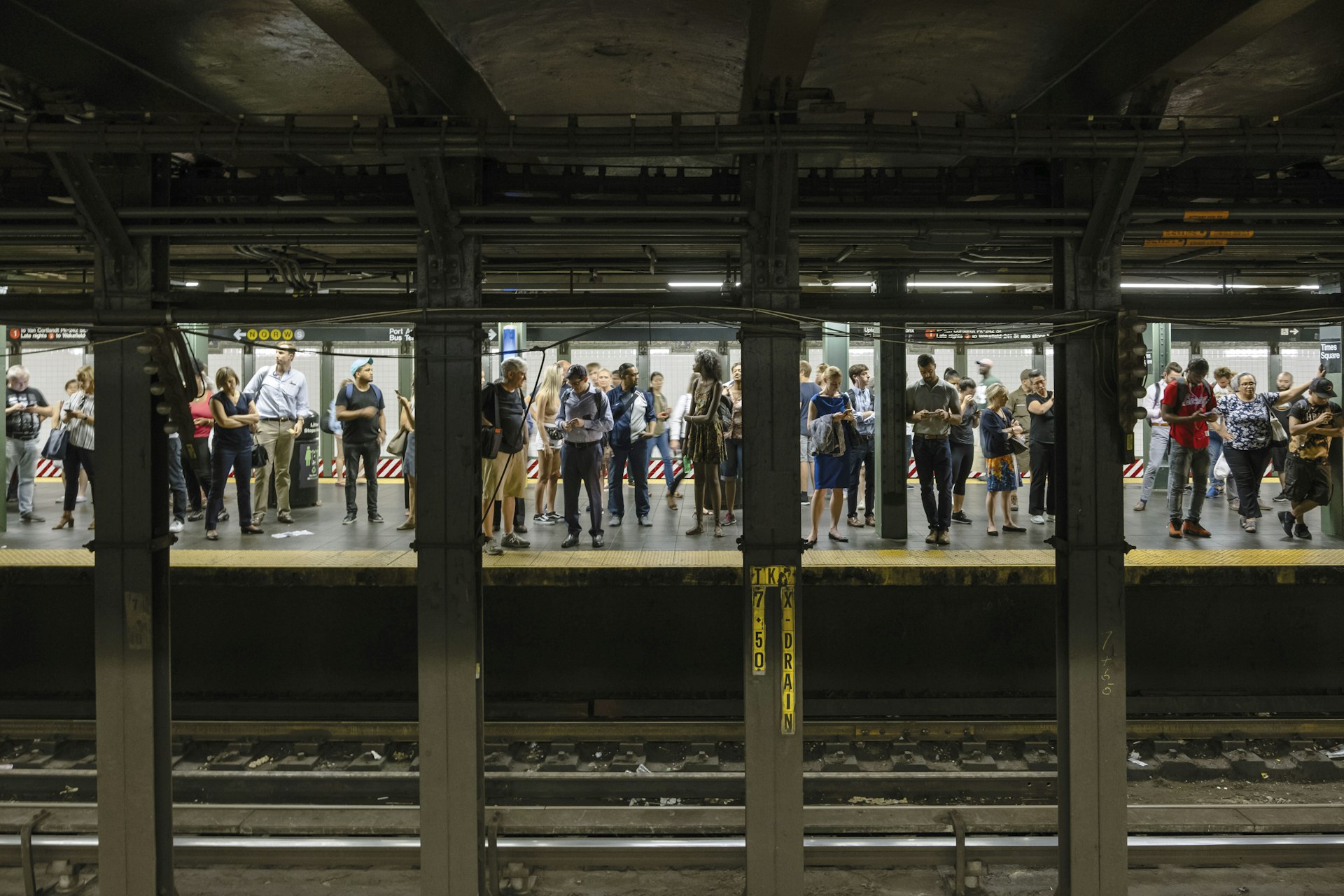 Passengers wait for a train at Times Square subway station in New York City