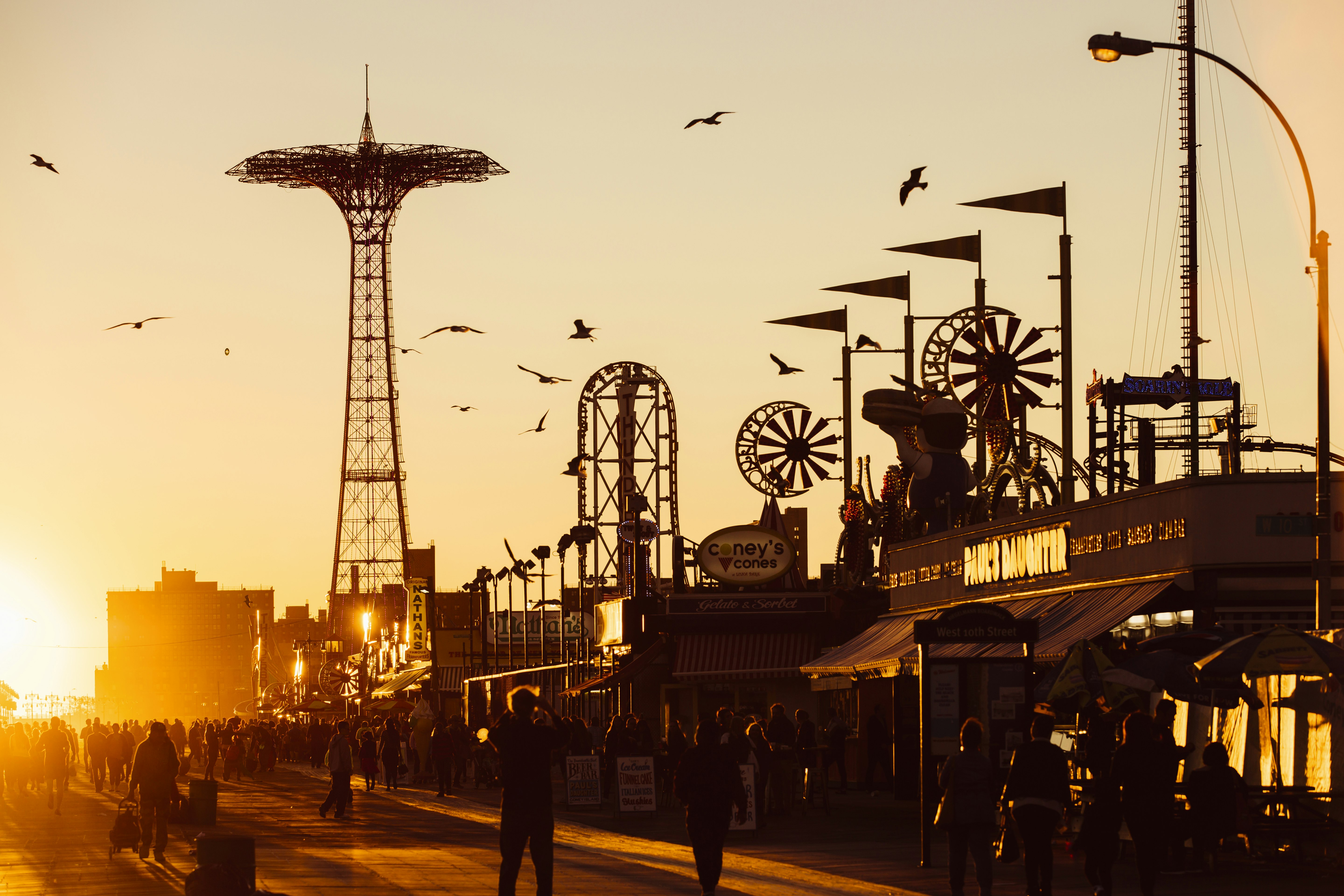 The attractions of Coney Island are silhouetted along the Boardwalk at sunset, Brooklyn, New York City, NY, USA