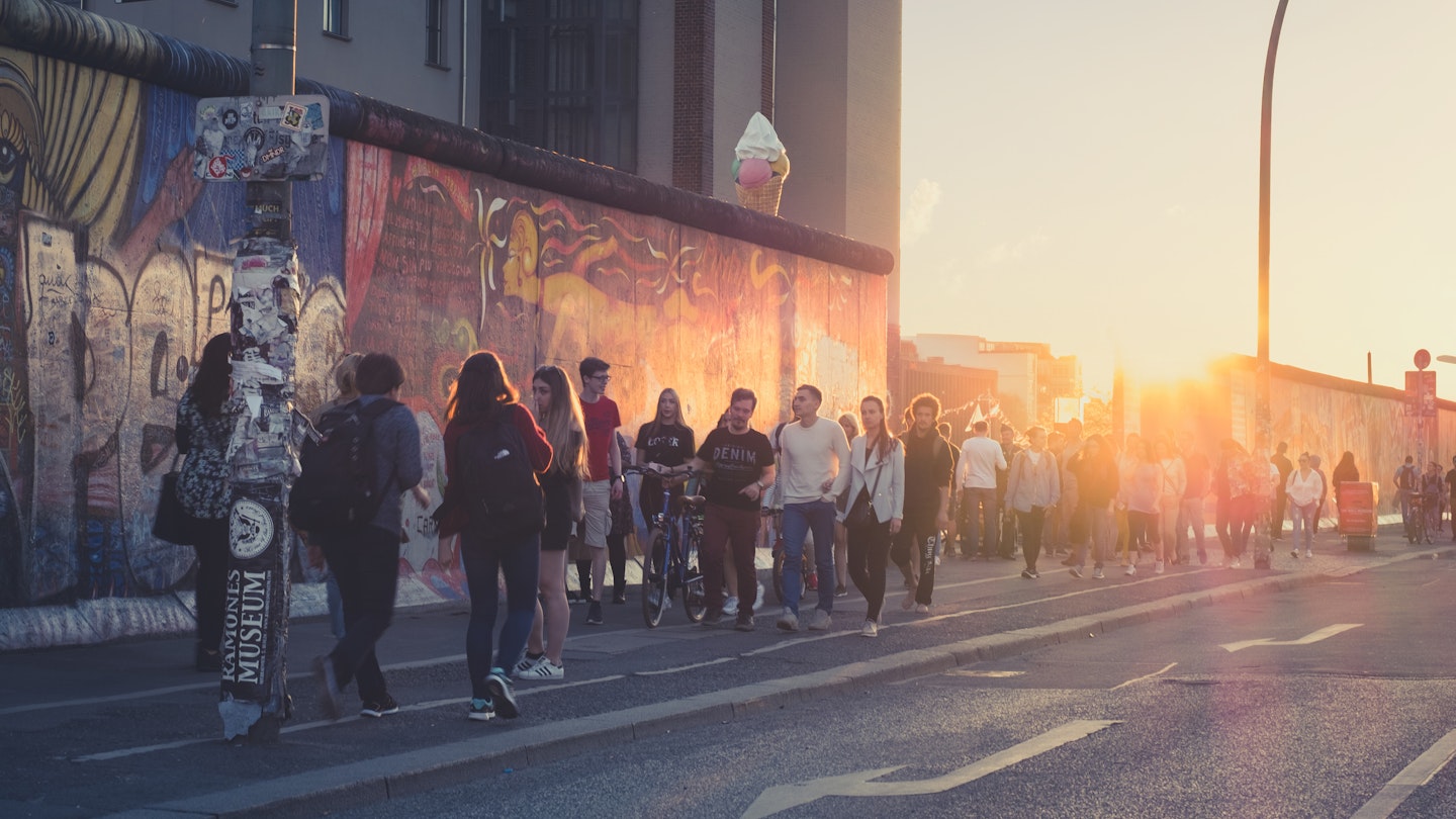 Berlin, Germany - april 2018: Young people walking at Berlin wall ( East Side Gallery) on summer day evening with sunset sky; Shutterstock ID 1074042023; your: AnneMarie McCarthy; gl: 65050; netsuite: Online Editorial; full: Best things to do in Berlin