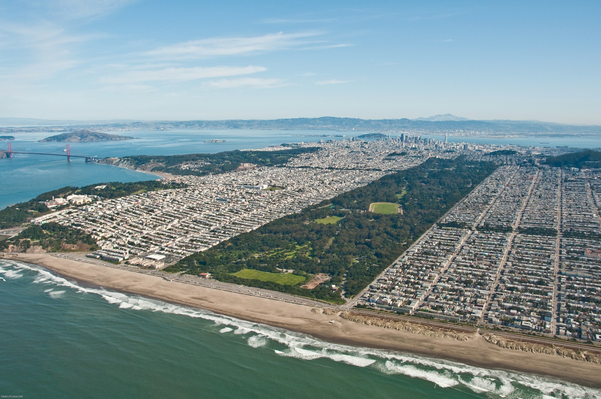 An aerial view of Golden Gate Park from the Pacific Ocean with the Golden Gate Bridge in the background.