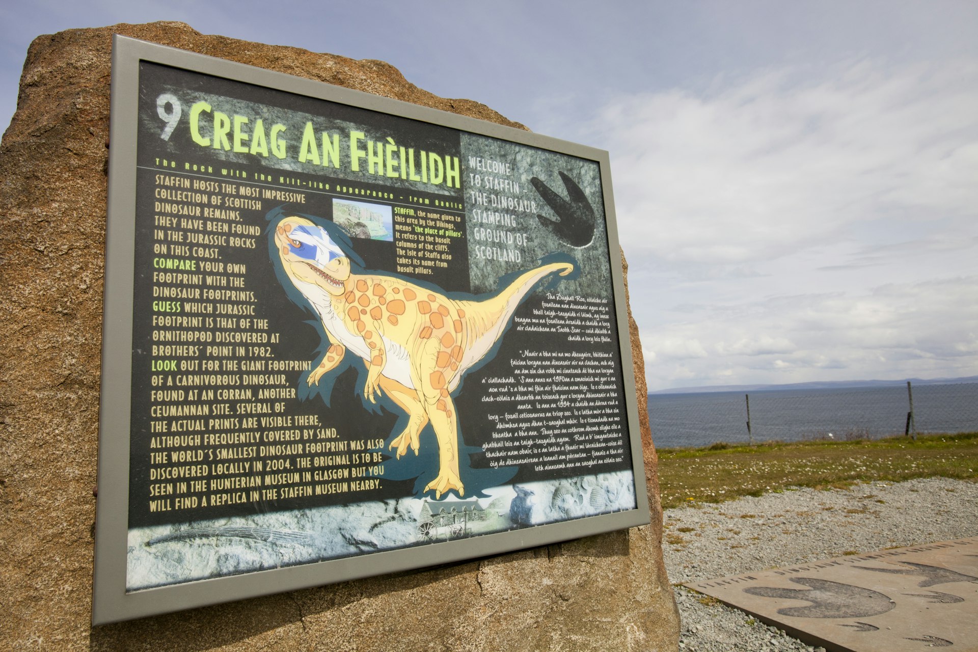 A sign about dinosaur footprints with a large dino illustration on the Isle of Skye