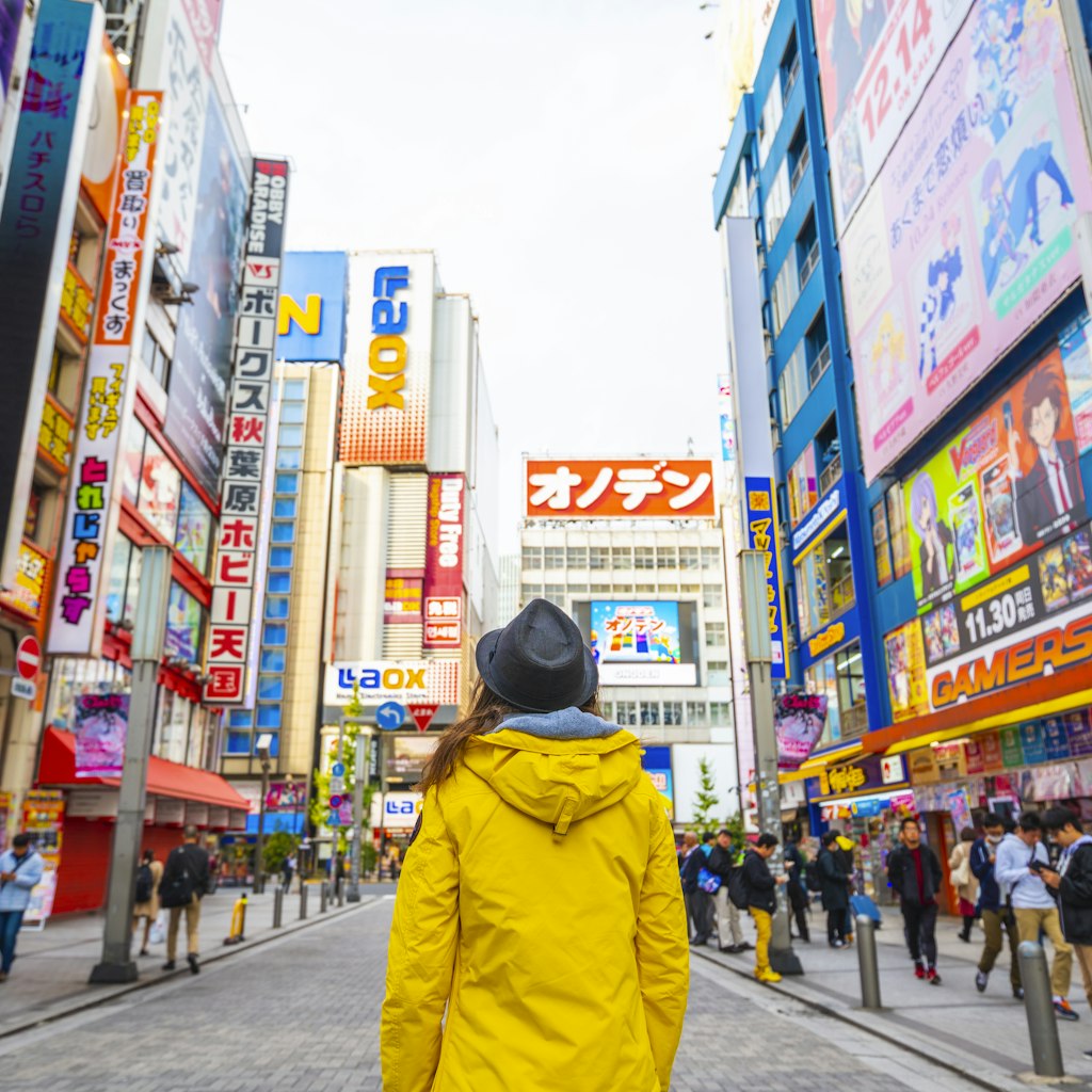 Woman with a yellow jacket walking in the electronic town district of Akihabara. 