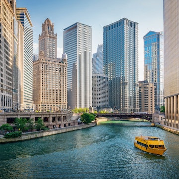 Yellow tour boat cruising on the Chicago River through the skyscrapers of downtown Chicago, towards Lake Michigan.
