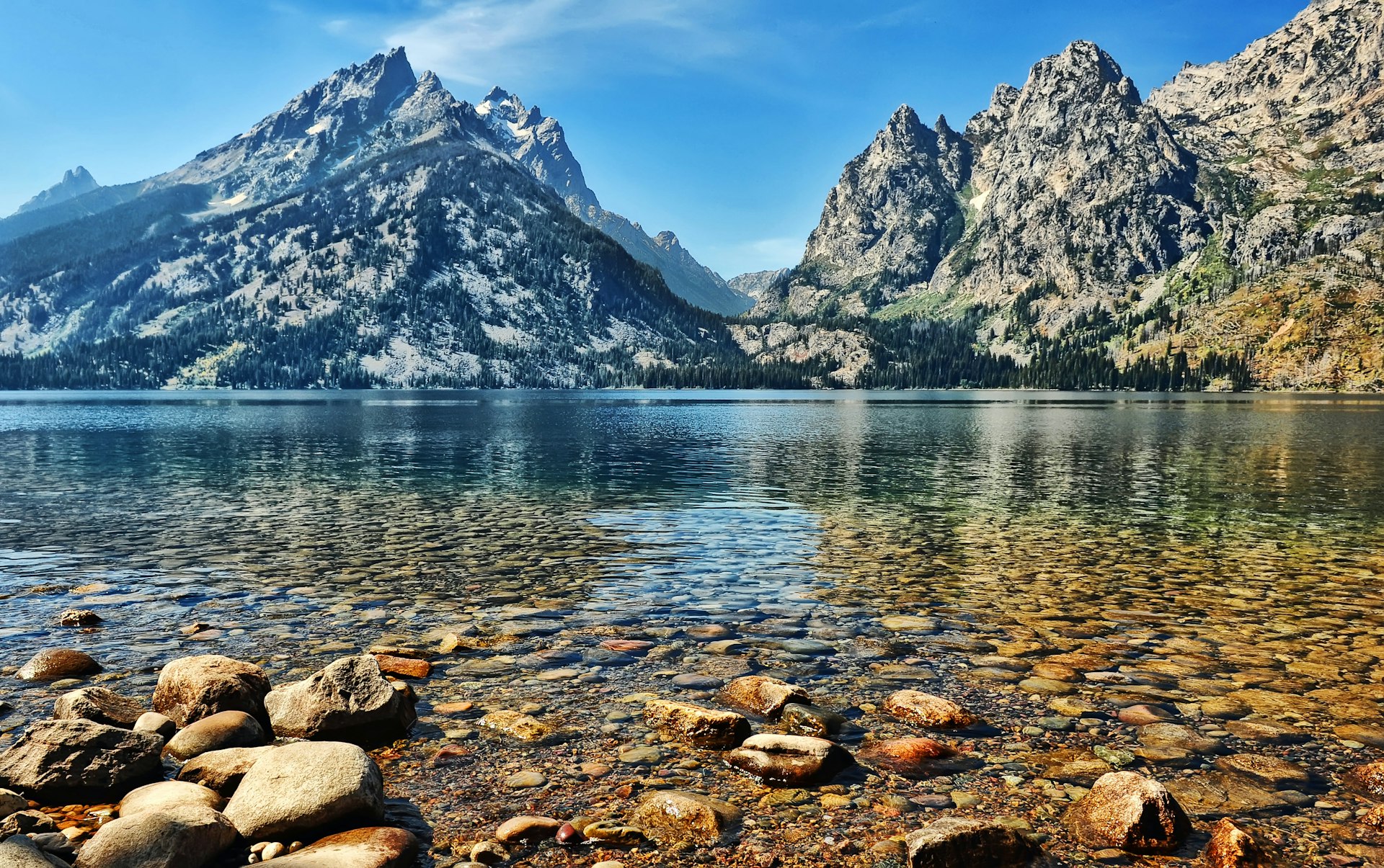 The clear water and stony bottom of Jenny Lake agains the backdrop of the Grand Teton peaks