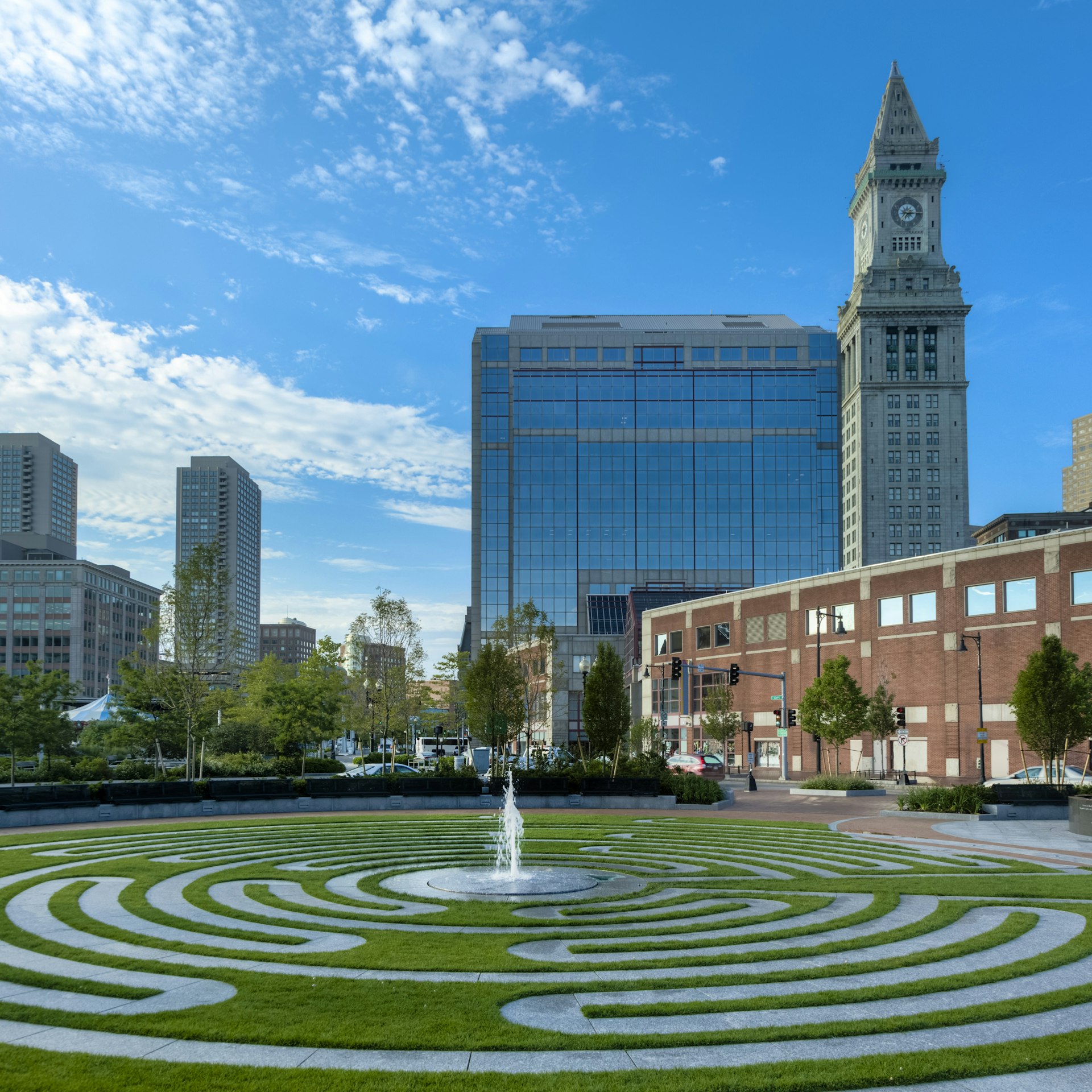 A labyrinth with a fountain in the middle of it and a city skyline in the background