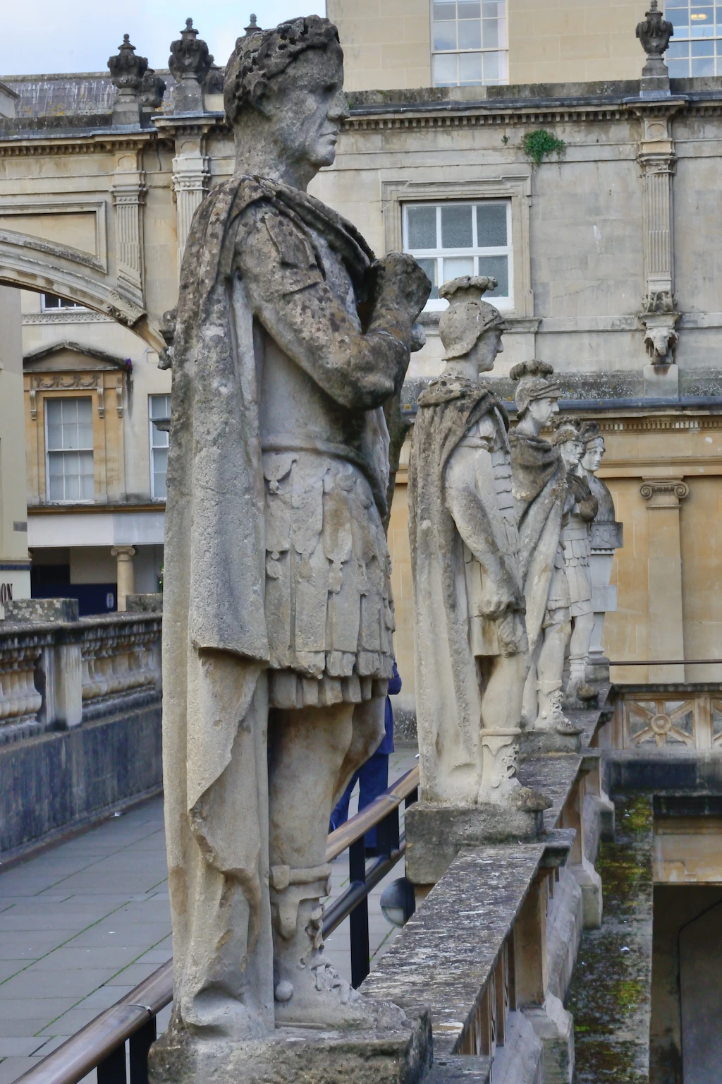 Roman Bath, Somerset, England Stone statues stand in a row above a Roman open-air pool